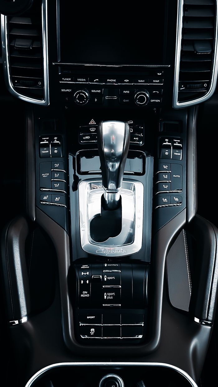 Closeup view of a luxury car center console and gear shift, highlighting sleek design.